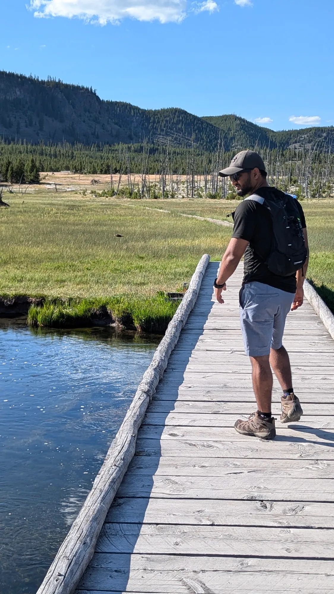 Varun Singh walking a boardwalk across a river in Yellowstone